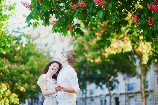 Lyckligt romantiskt par i Paris, kramar under rosa kastanjer i full blom — Stockfoto