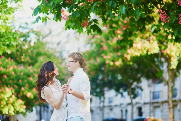 満開のピンクの栗の下で抱きしめるパリの幸せなロマンチックなカップル — ストック写真