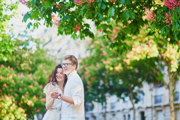 Feliz pareja romántica en París, abrazándose bajo castañas rosadas en plena floración —  Fotos de Stock