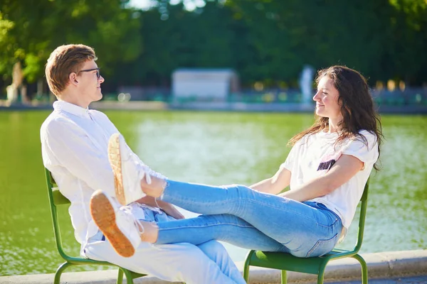 Šťastný romantický pár v Paříži, který sedí na tradičních zelených kovových křeslech v Tuileriích zahrádce — Stock fotografie