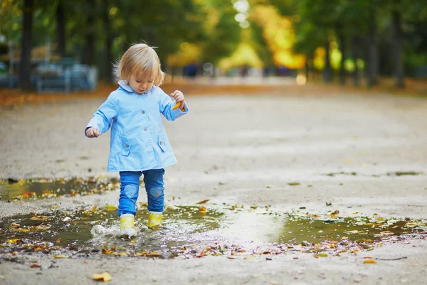 Niño con botas de lluvia amarillas y saltando en charco —  Fotos de Stock