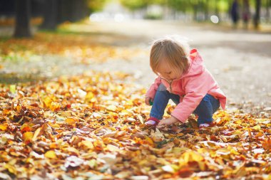 Paris, Fransa 'daki Tuileries bahçesinde koşan sevimli neşeli küçük kız. Mutlu çocuk sıcak ve güneşli sonbahar gününün tadını çıkarıyor. Çocuklar için açık hava sonbahar aktiviteleri