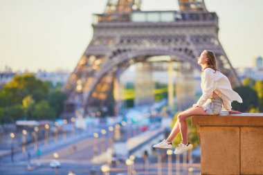 Paris 'teki Eyfel Kulesi' nin yanında oturan güzel genç kız. Turist Fransa 'da tatilinin tadını çıkarıyor