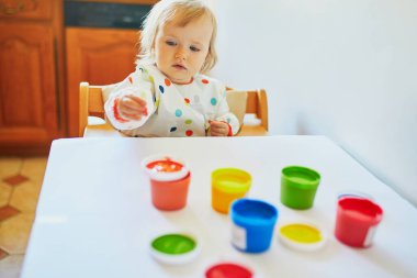 Anaokulunda ya da anaokulunda parmaklarıyla resim yapan sevimli küçük bir kız. Evde kalan çocuklar için yaratıcı oyunlar