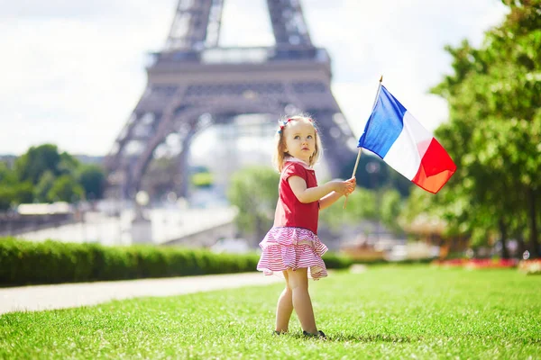 フランス パリのエッフェル塔の近くにフランスの国家三色の旗を持つ美しい幼児の女の子 7月14日 バスティーユの日 フランス国民の祝日 — ストック写真
