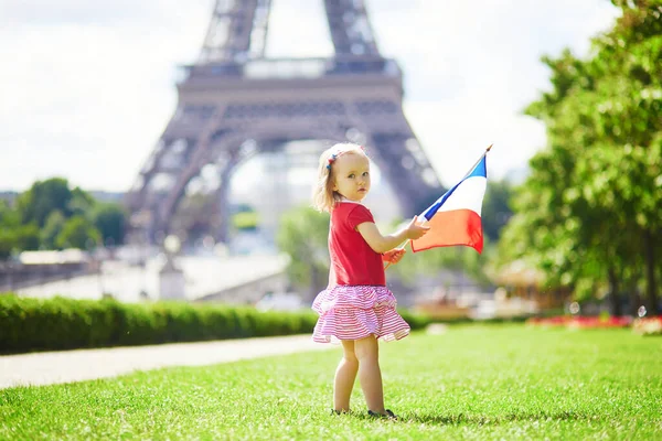 フランス パリのエッフェル塔の近くにフランスの国家三色の旗を持つ美しい幼児の女の子 7月14日 バスティーユの日 フランス国民の祝日 — ストック写真