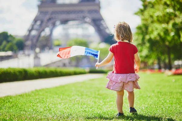 フランス パリのエッフェル塔の近くにフランスの国家三色の旗を持つ美しい幼児の女の子 7月14日 バスティーユの日 フランス国民の祝日 — ストック写真