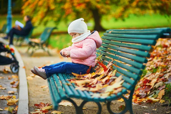 Förtjusande Liten Flicka Som Sitter Bänken Och Leker Med Fallna — Stockfoto