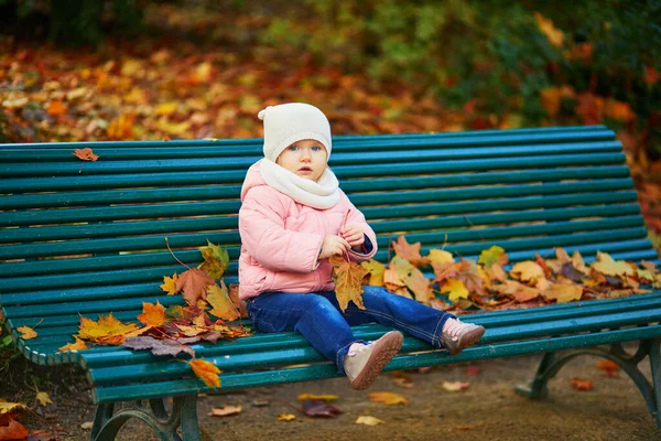 Urocza Dziewczynka Siedząca Ławce Bawiąca Się Spadającymi Liśćmi Parku Paryżu — Zdjęcie stockowe