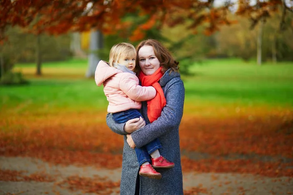 公園で秋の日に幼児の女の子と幸せな笑顔の女性 2つの明るい赤い葉の美しい家族 母親と娘が一緒に 子供と一緒に秋の活動 — ストック写真