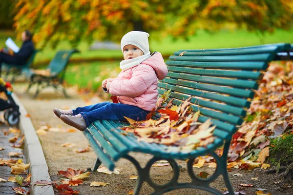 Adorable Niña Pequeña Sentada Banco Jugando Con Hojas Caídas Parque —  Fotos de Stock