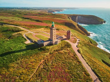 Cape Frehel 'in deniz feneriyle manzarası, Fransa' nın Brittany kentindeki en popüler turizm merkezlerinden biri. Ünlü GR34 izleme yolu boyunca yaygın olarak bilinen turist çekimini gösteren hava aracı görüntüsü