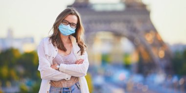 Paris 'teki Eyfel Kulesi' nin yanında duran ve Coronavirus salgını sırasında koruyucu maske takan genç bir kız. Fransa 'da salgın ve tecrit. Karantinadan sonra Fransa 'da tatil yapan turistler