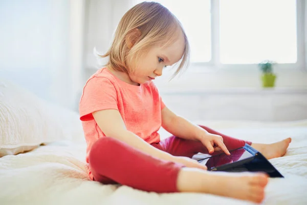 stock image Toddler girl with digital tablet at home. Child watching cartoons. Kid using gadget to communicate with friends or kindergartners. Education and distance learning for kids. Stay at home entertainment