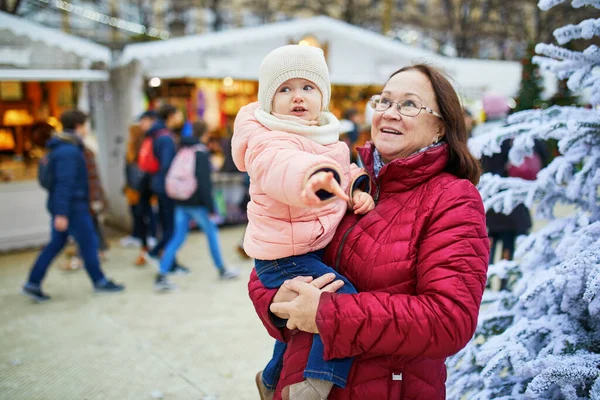 フランスのクリスマスマーケットで女性と愛らしい幼児の女の子 祖母と孫娘が一緒に屋外で季節の冬の休日を楽しむ — ストック写真