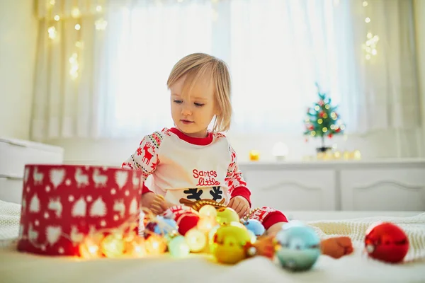 Pijama Giyen Noel Süsleriyle Yatakta Oynayan Küçük Mutlu Bir Kız — Stok fotoğraf