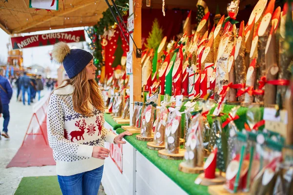 フランスの伝統的なクリスマスマーケットで休日の装飾を購入する美しい若い女性 — ストック写真
