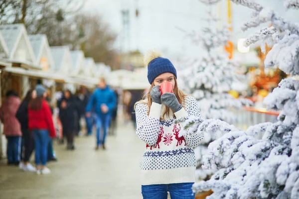 フランスのパリのクリスマスマーケットで幸せな若い女性 クリスマスツリーの近くでホットワイン コーヒーを飲む女の子 クリスマスと新年の野外活動 — ストック写真