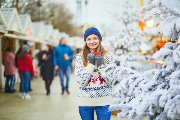 フランスのパリのクリスマスマーケットで幸せな若い女性 クリスマスツリーの近くでホットワイン コーヒーを飲む女の子 クリスマスと新年の野外活動 — ストック写真