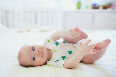 Sırtüstü yatıp ayaklarına dokunan tatlı bir kız çocuğu. Mutlu sağlıklı çocuk evde, kreşte.