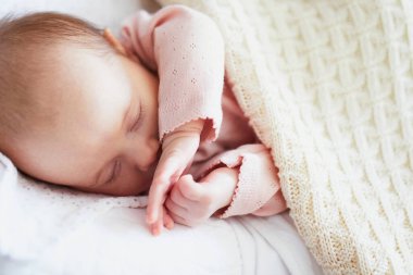 Bebek odasında örgü örülü battaniyenin altında uyuyan sevimli bir kız.