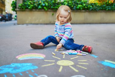 Asfalta renkli tebeşirler çizen sevimli küçük kız. Küçük çocuklar için açık hava aktiviteleri ve yaratıcı oyunlar