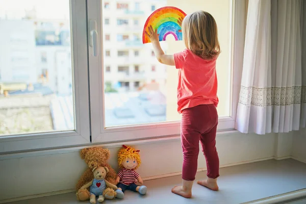 Förtjusande Liten Flicka Fästa Regnbåge Ritning Till Fönsterglas Som Tecken — Stockfoto