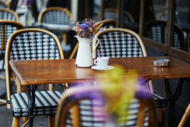 Geleneksel Paris açık hava kafe masası. Fransa, Paris 'te boş bir restoranda bir fincan kahve ve kurutulmuş çiçeklerle dolu sürahi.