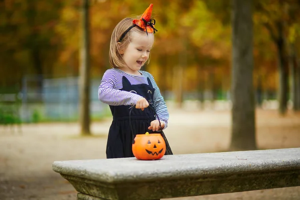 Siyah kedi kıyafetli, etekli, turuncu balkabağı kovalı, şeker mi şaka mı oynayan sevimli bir kız. Mutlu çocuk Paris, Fransa 'da Cadılar Bayramı' nı kutluyor