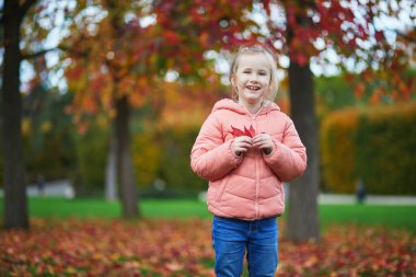 Neşeli küçük kız Paris, Fransa 'daki sonbahar parkında yürüyüşünün tadını çıkarıyor.