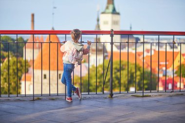 Sırt çantalı sevimli anaokulu kızı Estonya 'nın Tallinn şehrinin eski manzarasının tadını çıkarıyor.
