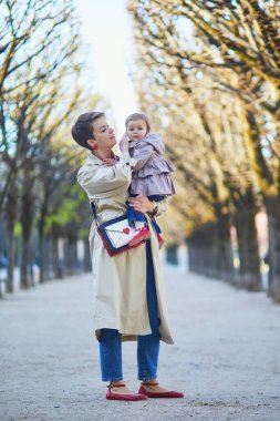 Güzel genç anne ve tapılası küçük kızı Paris, Fransa 'da parkta birlikte yürüyorlar.