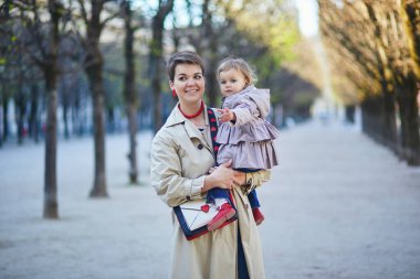 Güzel genç anne ve tapılası küçük kızı Paris, Fransa 'da parkta birlikte yürüyorlar.