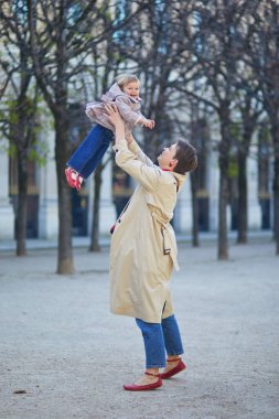 Güzel genç anne ve tapılası küçük kızı Paris, Fransa 'da parkta birlikte yürüyorlar.