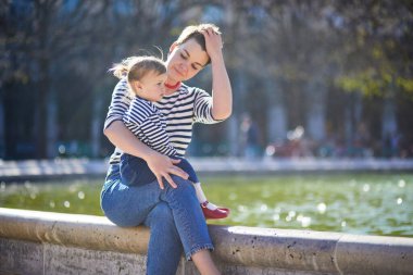Güzel genç anne ve tapılası küçük kızı Paris, Fransa 'da parkta birlikte yürüyorlar.