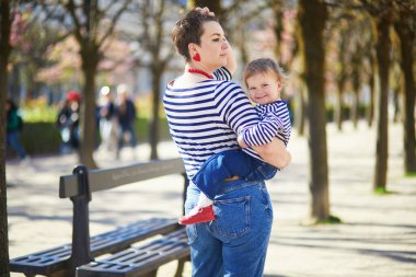 Güzel genç anne ve tapılası küçük kızı Paris, Fransa 'da parkta birlikte yürüyorlar.