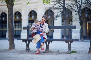 Güzel genç anne ve tapılası küçük kızı Paris, Fransa 'da parkta birlikte yürüyorlar.