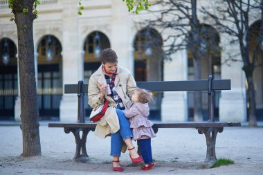 Güzel genç anne ve tapılası küçük kızı Paris, Fransa 'da parkta birlikte yürüyorlar.