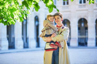 Güzel genç anne ve tapılası küçük kızı Paris, Fransa 'da parkta birlikte yürüyorlar.