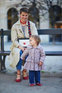 Güzel genç anne ve tapılası küçük kızı Paris, Fransa 'da parkta birlikte yürüyorlar.