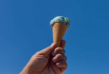 Erkek el dondurma külahı gökyüzü arka plan üzerinde tutarak.