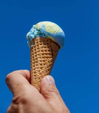 Erkek el dondurma külahı gökyüzü arka plan üzerinde tutarak.