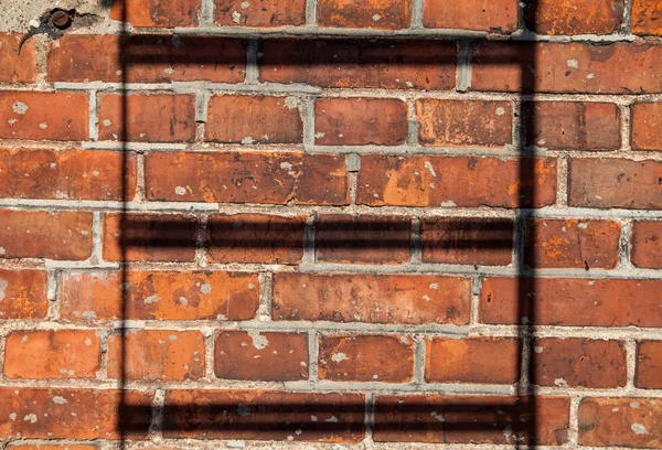 Stair shadows on red brick wall.