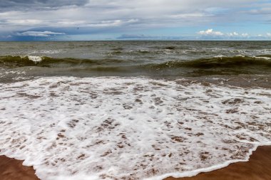 Bir bulutlu gökyüzü ve köpük su denize sıfır fırtınada.