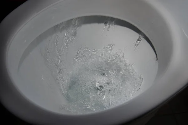 Water flushing in toilet.