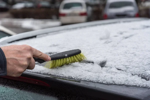 Человек чистит машину от снега . — стоковое фото