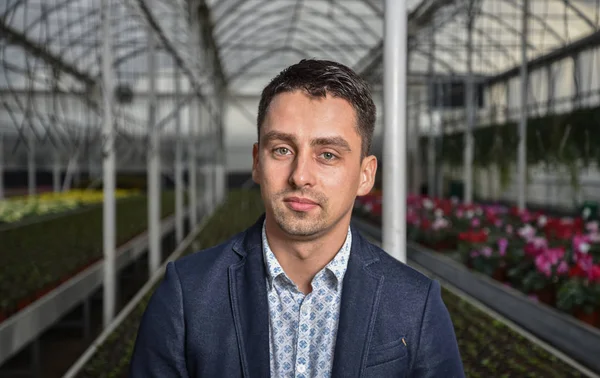 Smiling young man in greenhouse.