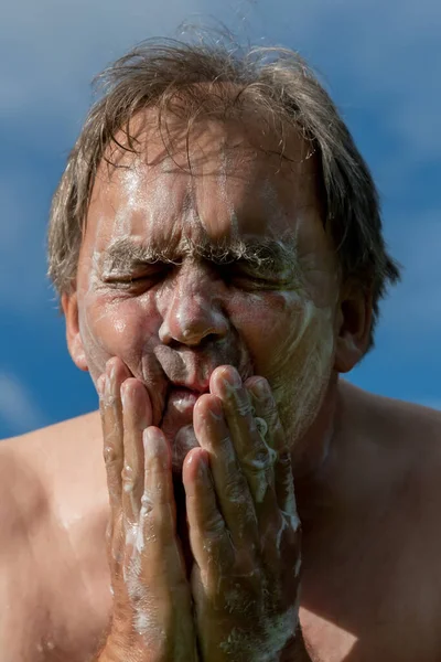 Adult man wash a face on an nature.