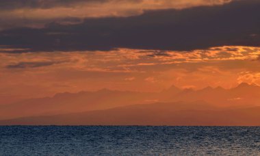 Kuzey Tian Shan dağ zirveleri turuncu gündoğumu ışık, Issyk-Kul göl kıyısı, doğu Kırgızistan