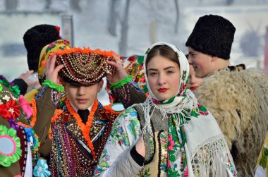 Chernivtsi, Ukrayna - 13 Ocak 2019: Genç Ukraynalı erkek ve kadın halk mimarisinin Açık Hava Müzesi'nde etnik Festivali sırasında Malanka şarkı gerçekleştirin. Geleneksel Ulusal elbise karnaval askeri giymiş erkekler, Bukovina, giymiş kadın